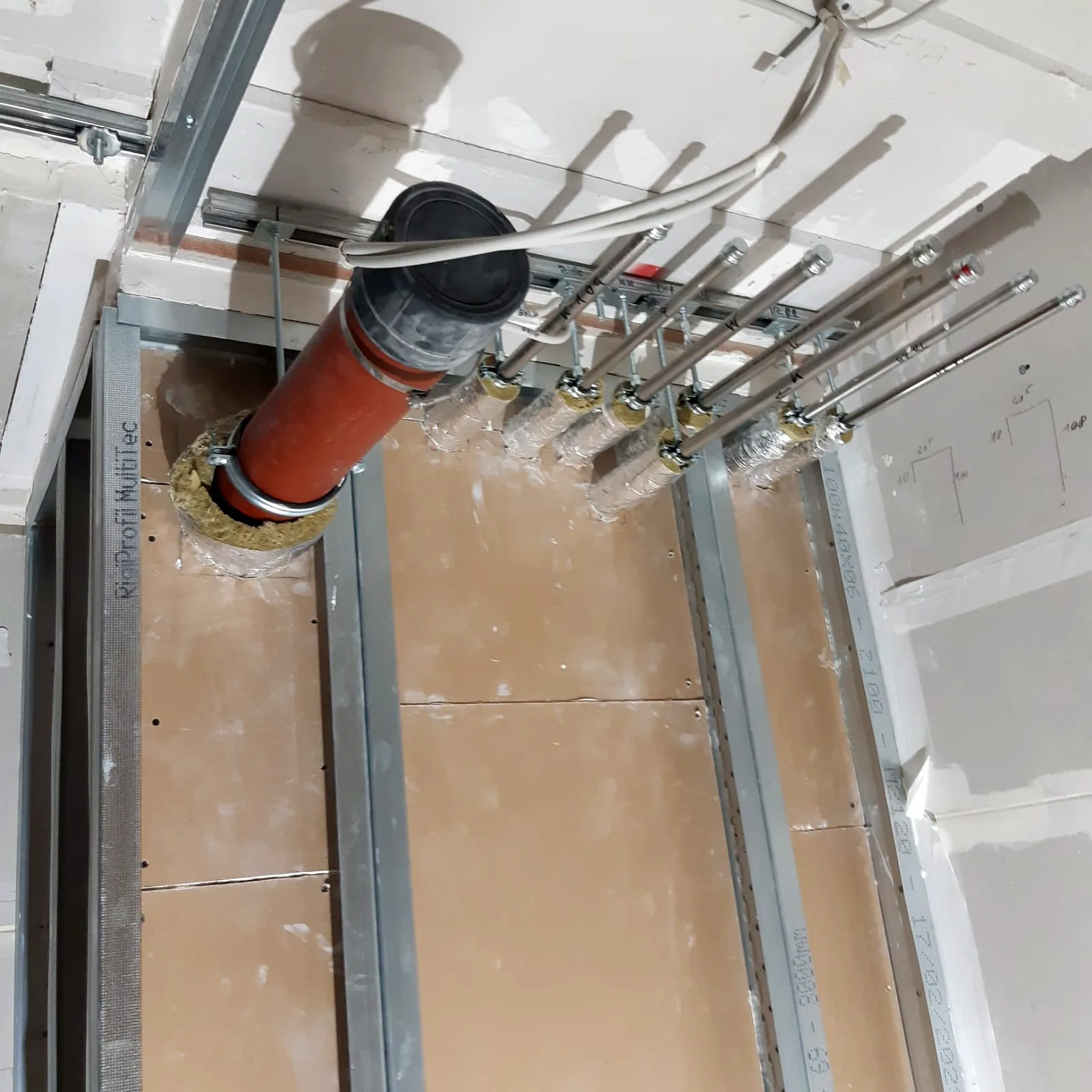 Installationsschacht in Trockenbau mit Metallständern, Gipskartonbeplankung und gedämmten Rohrdurchführungen