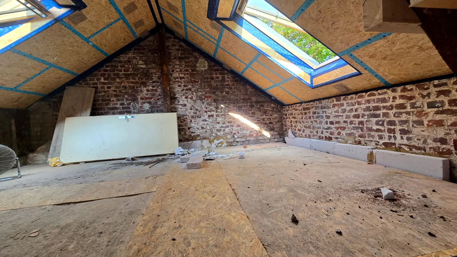 Dachgeschoss im Altbau mit Dachfenstern, Ziegelwand und OSB-Dachflächen vor dem Trockenbau